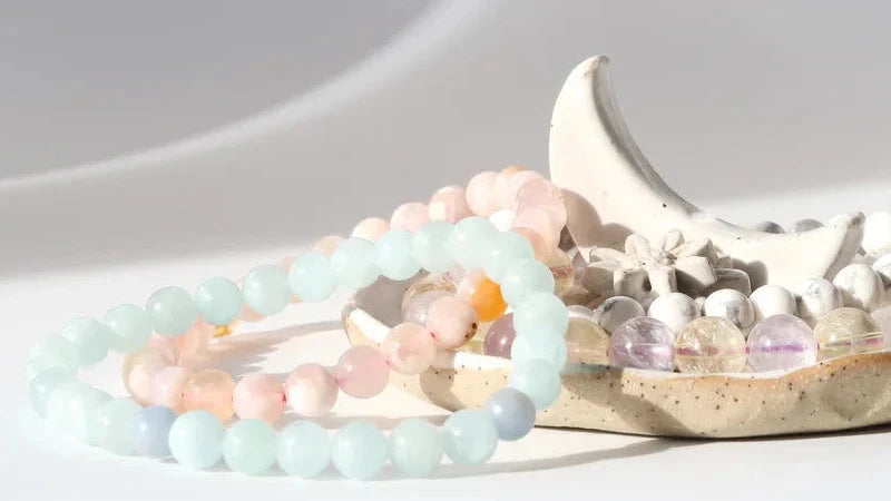 Two beaded bracelets on a ceramic dish with a white background