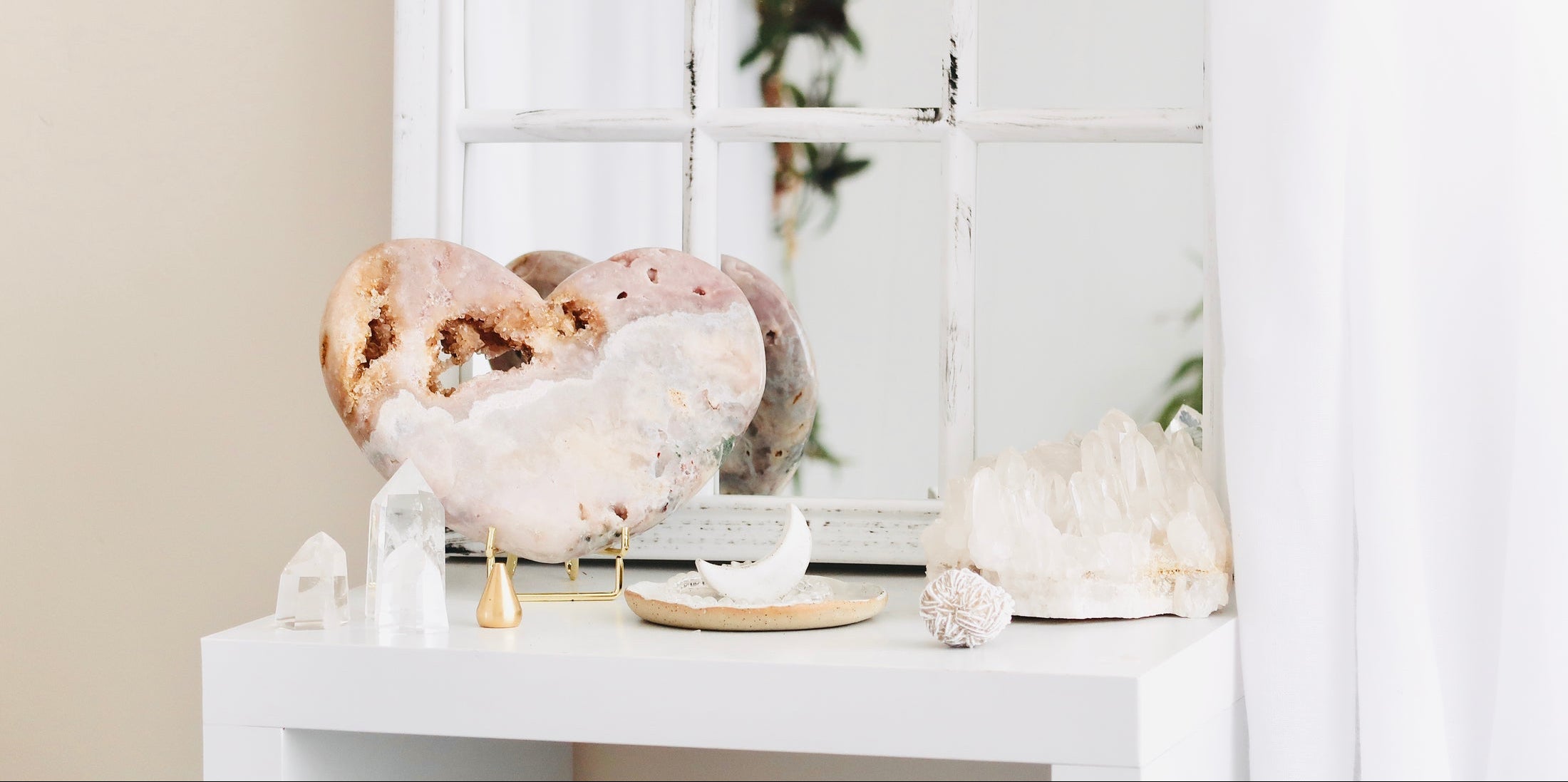 Decorative display of crystals and sculptures on a white shelf with a neutral background