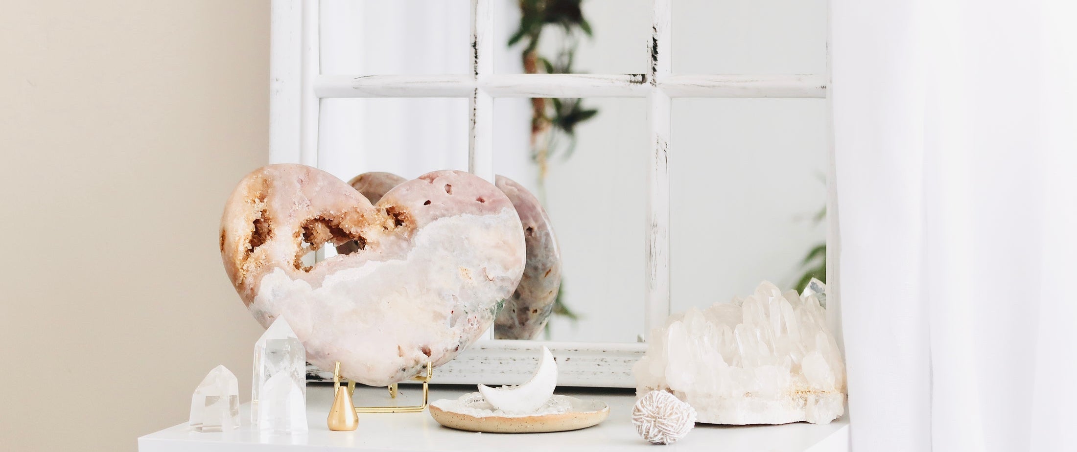 Decorative display of crystals and sculptures on a white shelf with a neutral background