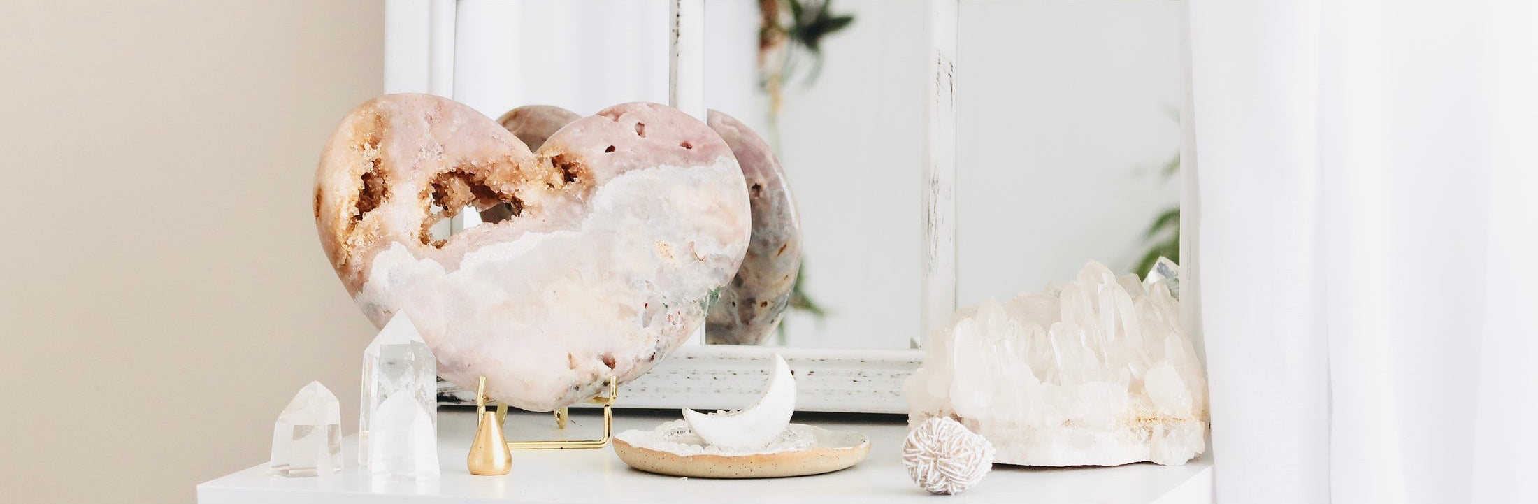 Decorative display of crystals and sculptures on a white shelf with a neutral background