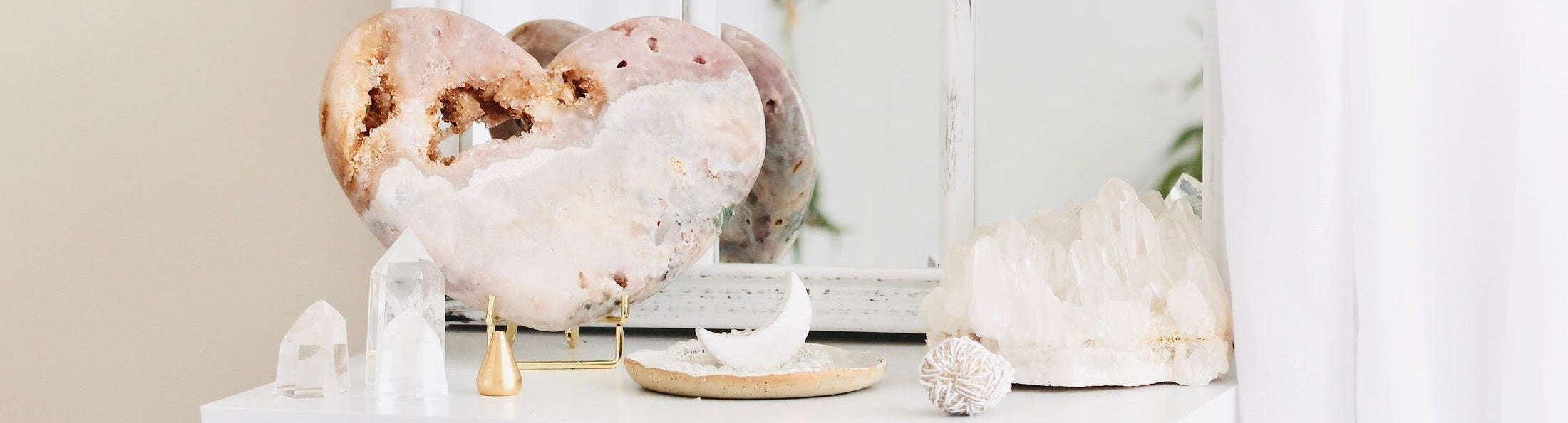 Decorative display of crystals and sculptures on a white shelf with a neutral background