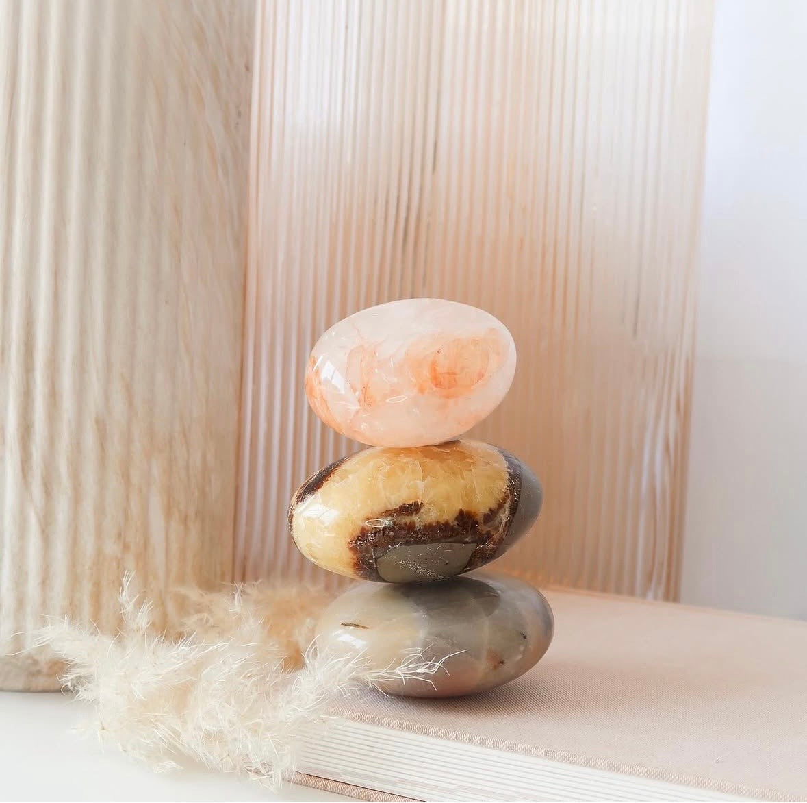 Stack of three colorful stones on a white surface with a soft, blurred background