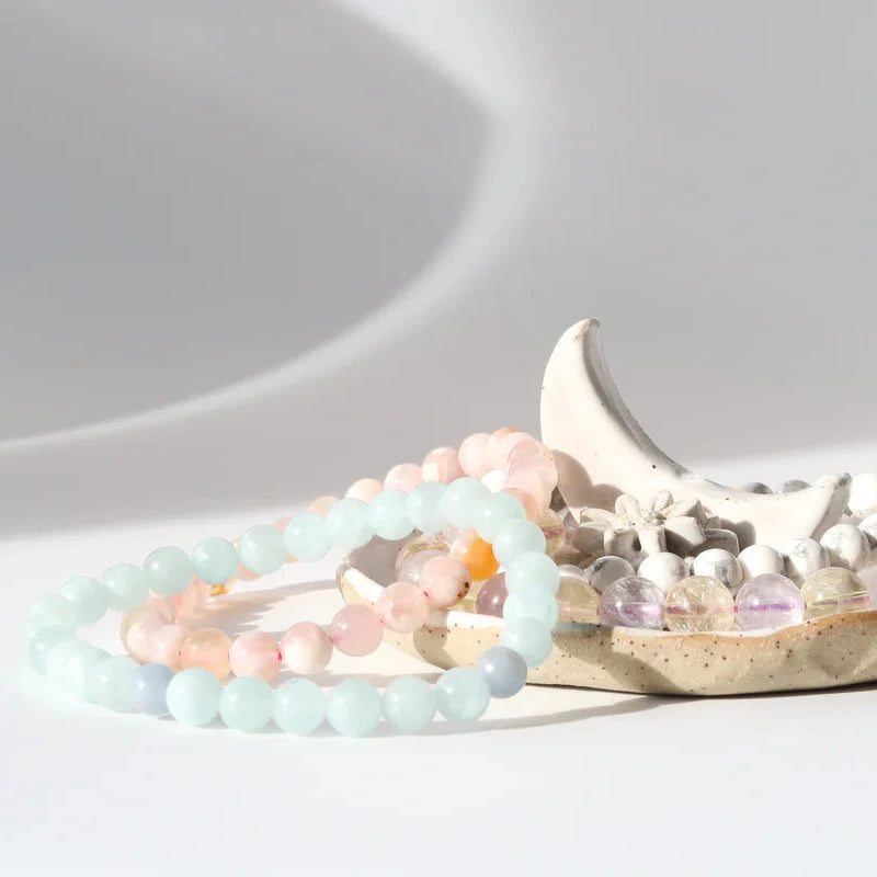 Two beaded bracelets on a ceramic dish with a white background